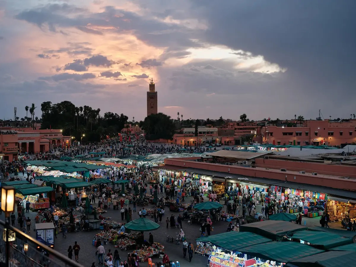 Jemaa el-Fna square at sunset with market stalls and the Koutoubia minaret on the skyline