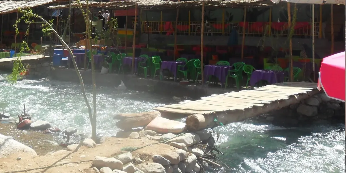 Riverside cafe terraces and a wooden footbridge over the Ourika river